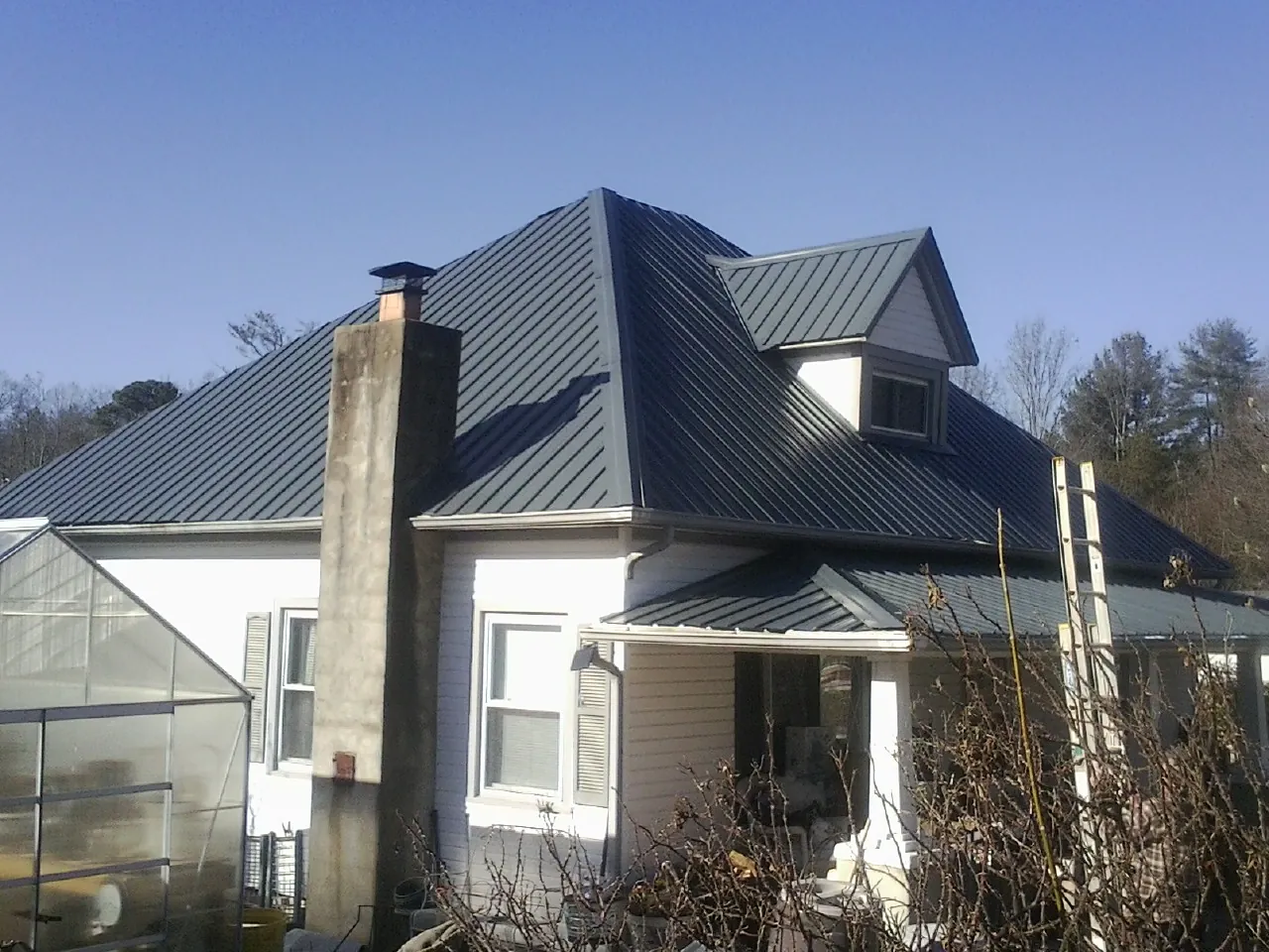 Dark blue standing seam metal roof on a white farmhouse with dormer — Slate & Tile Roof Repair by Roofing Brothers in Berne