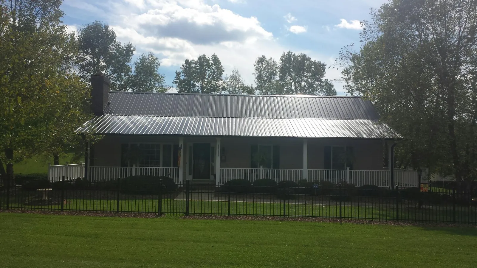 Gray metal roof on a brick ranch with a full width front porch — Gutter Guard Installation work by our crew in Berne